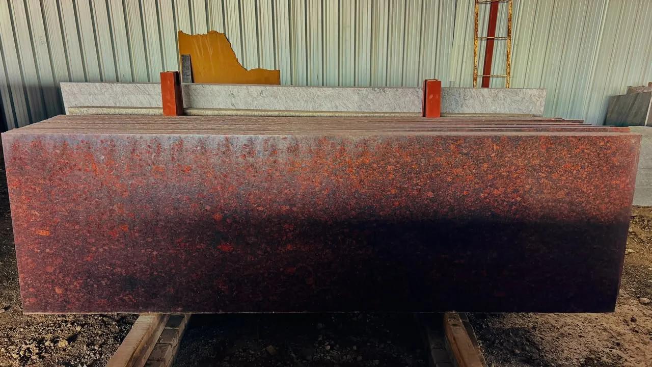 Red and black natural granite slabs displayed inside the covered warehouse