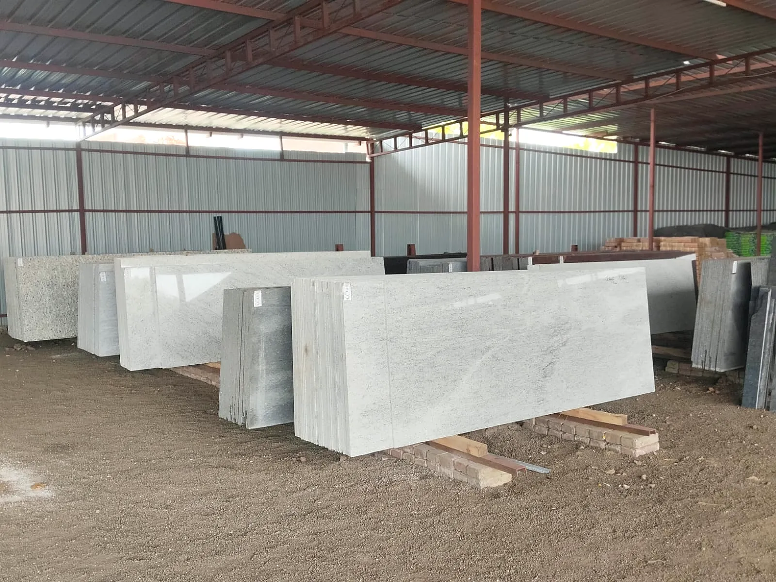 Full-length white granite slabs stacked on timber in the Paras Home Decor stock yard