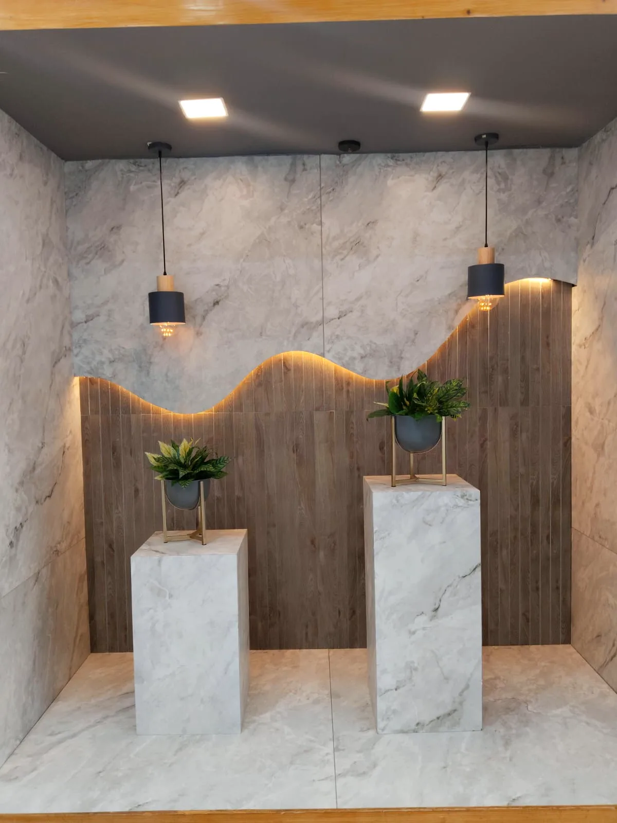 White marble-look tile display with wood-finish tile wave wall and pedestals