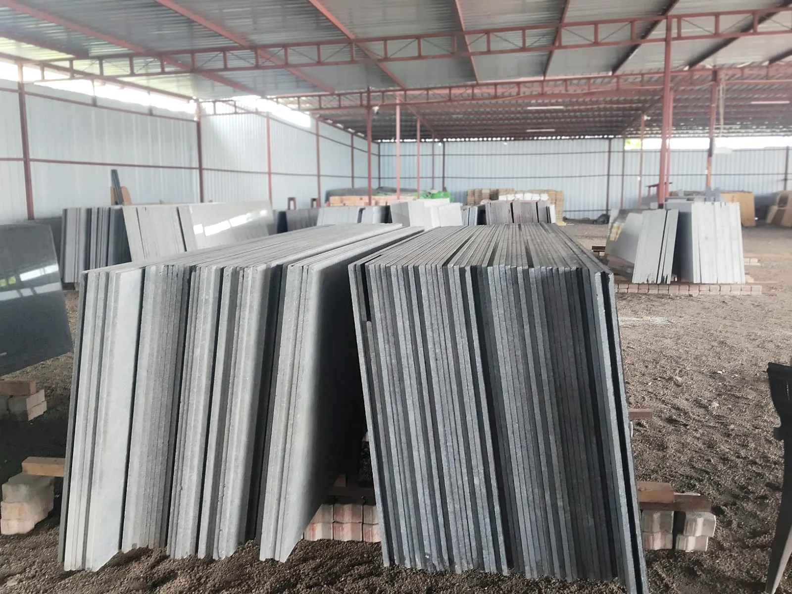 Rows of grey and black granite slabs racked inside the covered stock yard