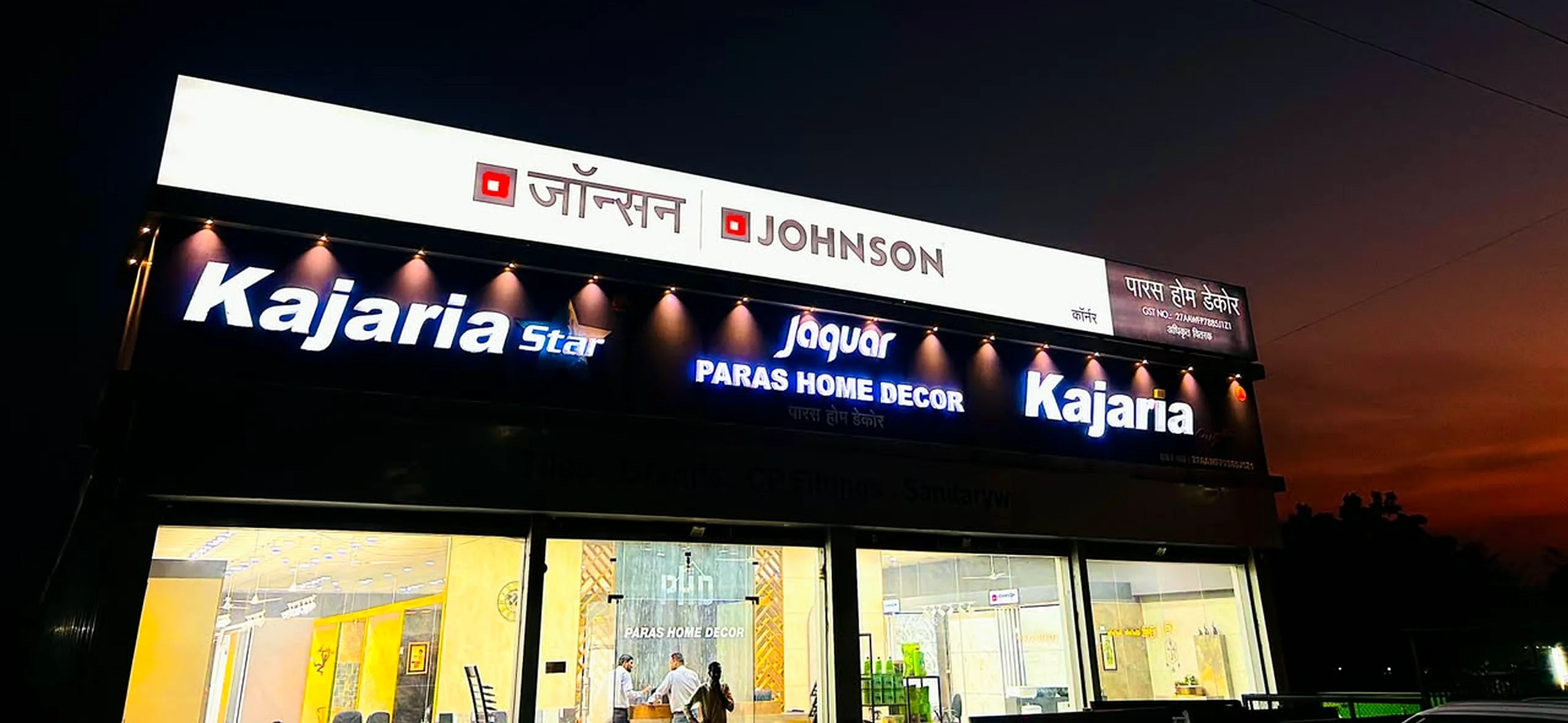 Paras Home Decor showroom on Beed Bypass Road at dusk, with Kajaria, Johnson and Jaquar signage lit above the glass front