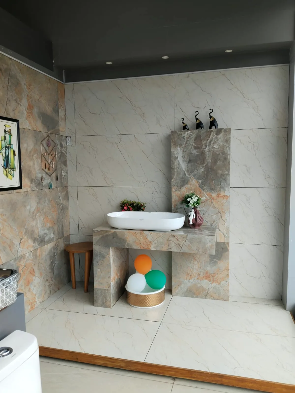 Beige marble-look tile bay with a stone-clad counter and wide white wash basin