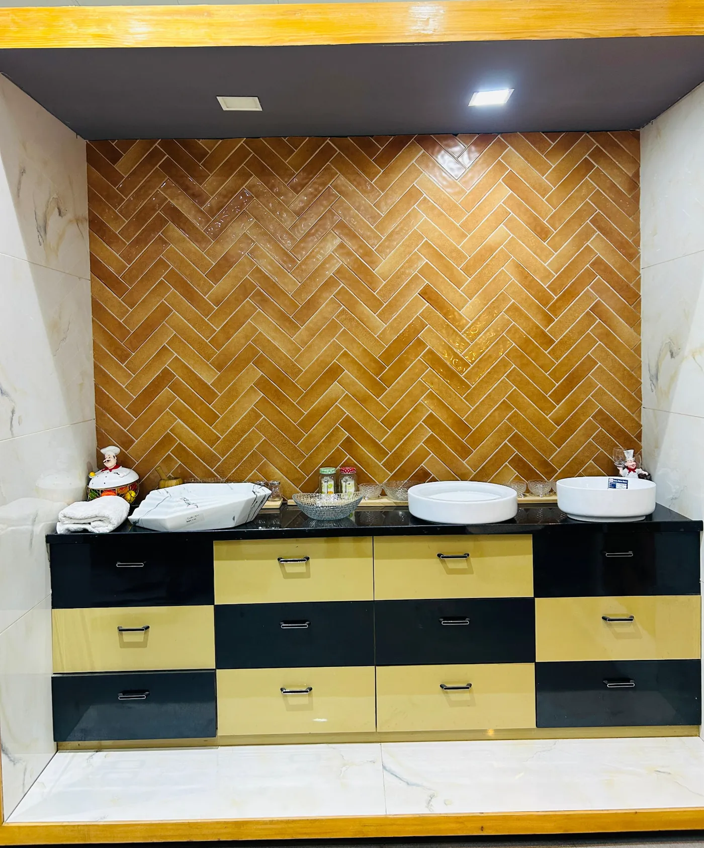Golden herringbone tile backsplash display with twin table-top basins