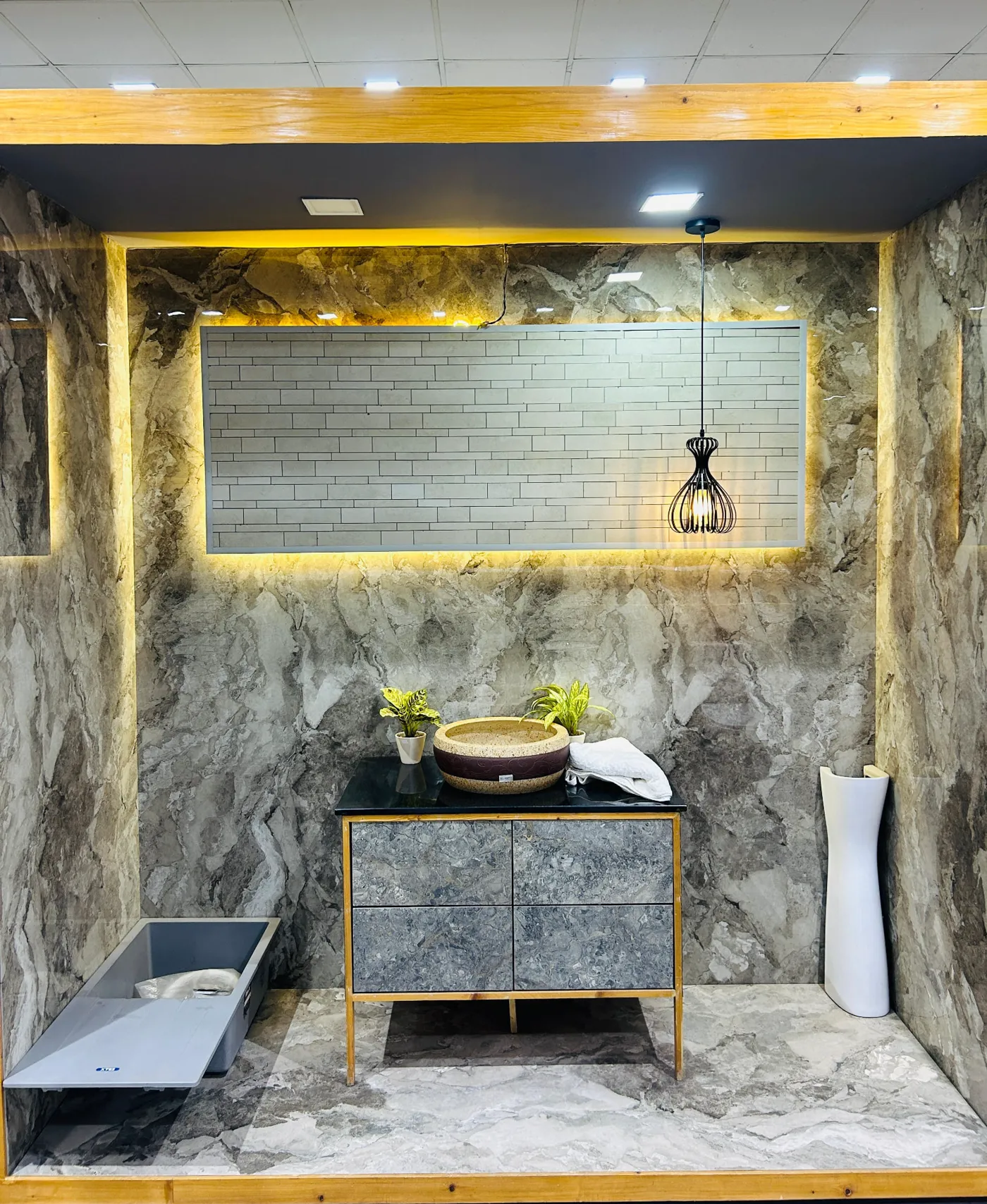 Grey marble-look tile vanity bay with backlit brick tile panel, counter basin and mirror frame