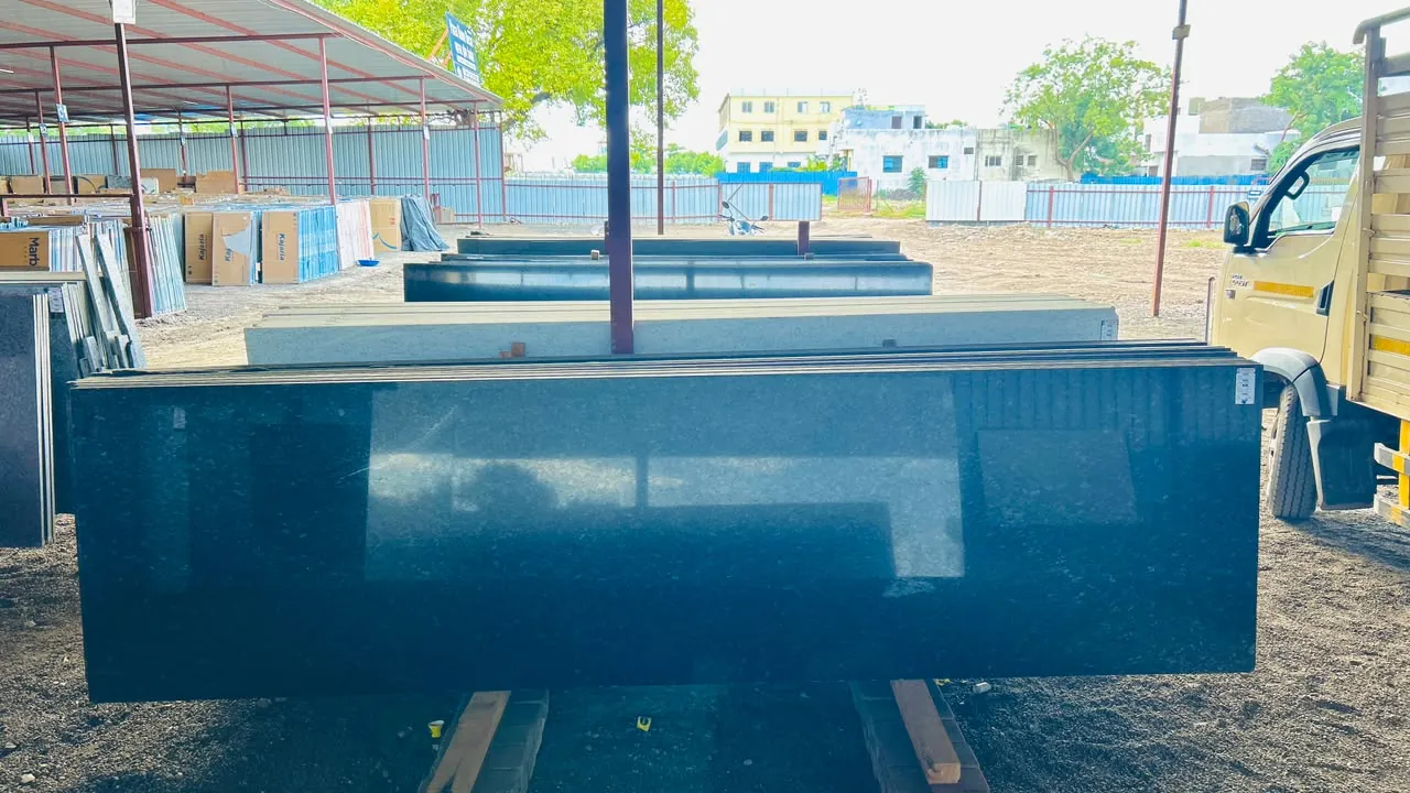 Polished dark granite slab with additional slabs arranged behind it in the yard