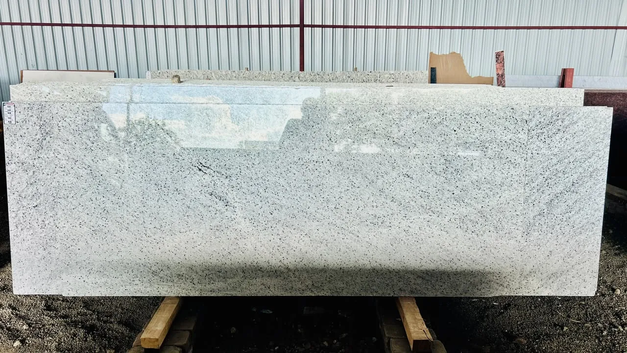Full polished white speckled granite slab displayed in the warehouse