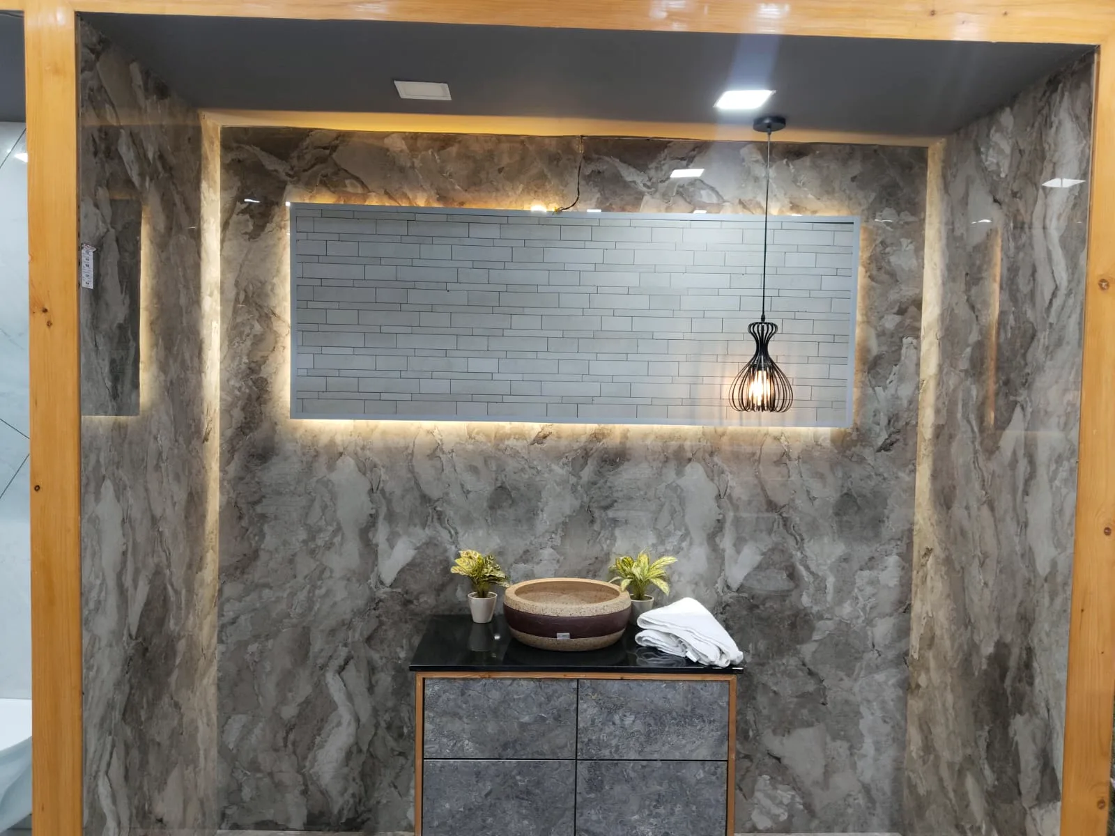 Grey marble-look tile vanity nook with backlit brick tile panel and stone basin