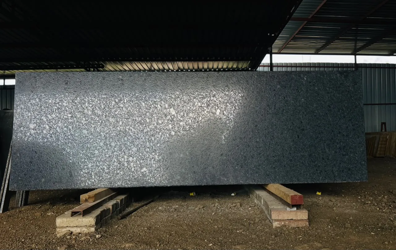 Full steel-grey granite slab displayed under the covered warehouse roof