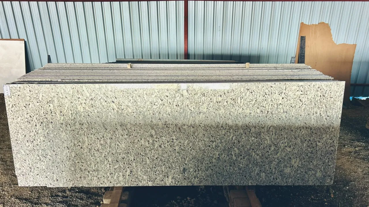 Light patterned granite slabs stacked together against the warehouse wall